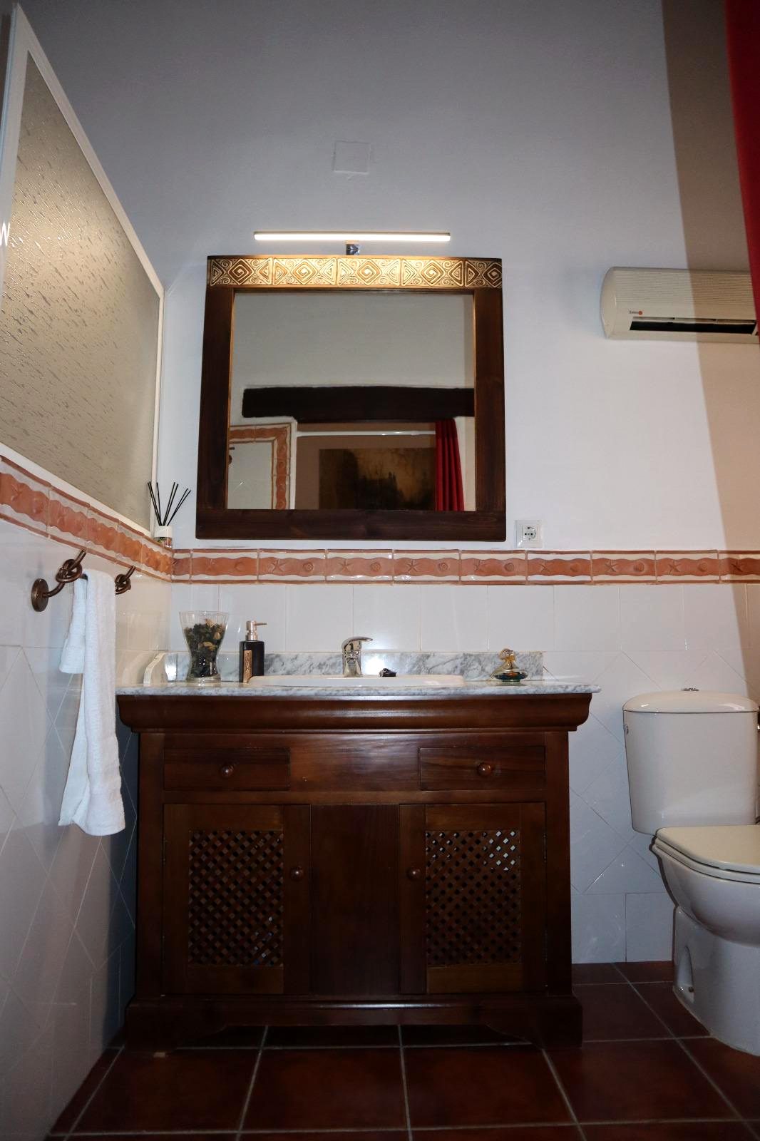 Baño con lavabo de madera, espejo y azulejos
