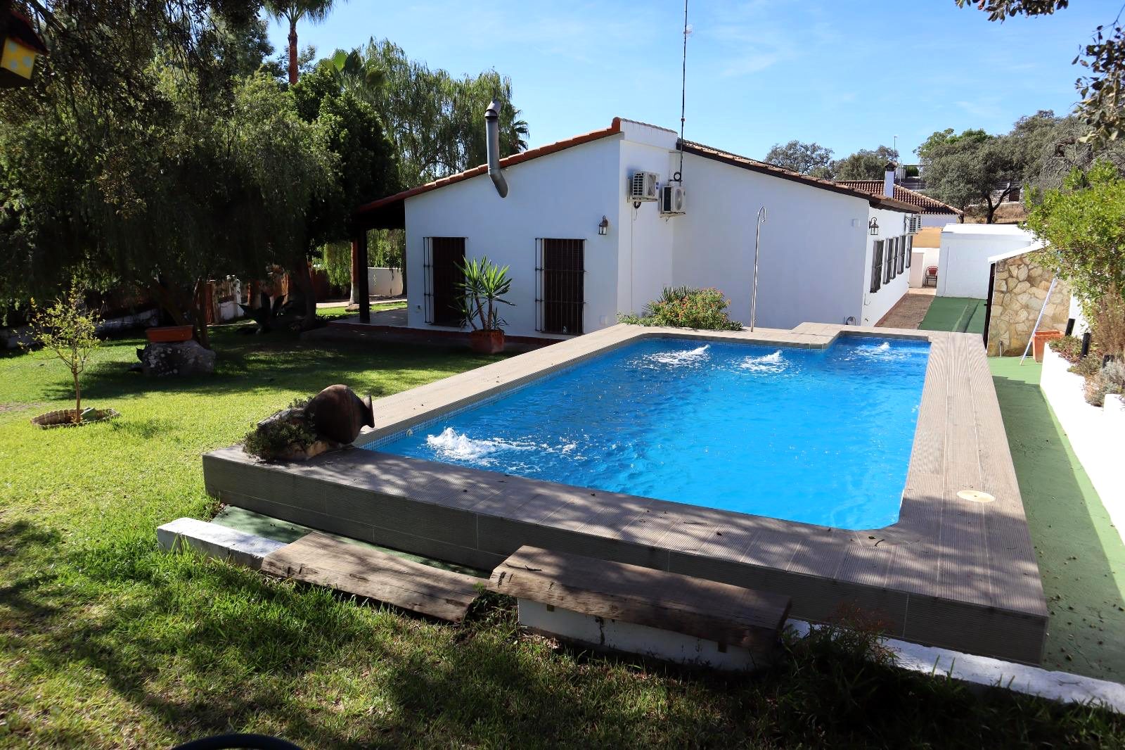 Piscina privada rodeada de césped y la casa al fondo
