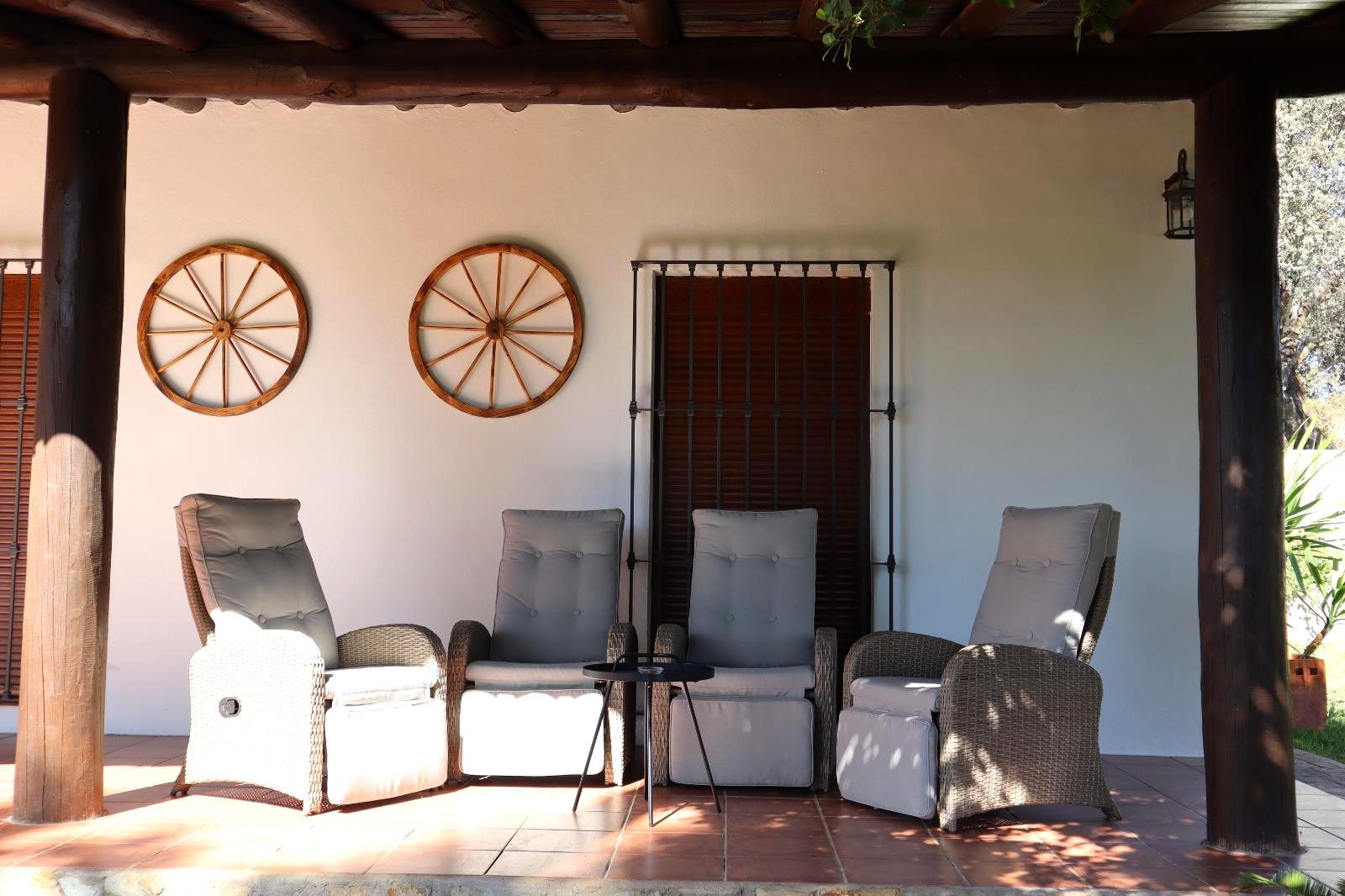 Terraza cubierta con sillones y ruedas de carro decorativas